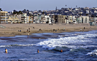 People at beach against clear sky