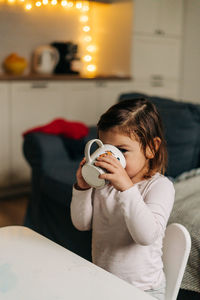 Portrait of cute girl drinking milk while sitting at home