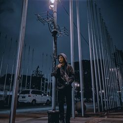 Portrait of young woman standing against illuminated building at night