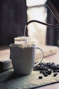 Close-up of water pouring in coffee cup on table