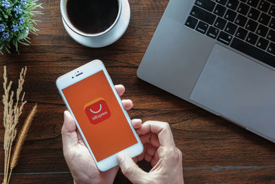 Midsection of man using mobile phone on table