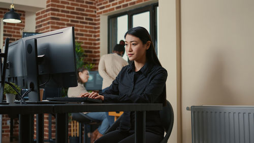 Portrait of young woman using laptop at office