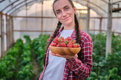 Portrait of young woman holding strawberries