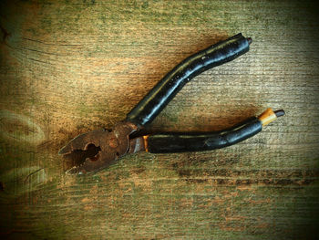 High angle view of old rusty pliers on wooden table