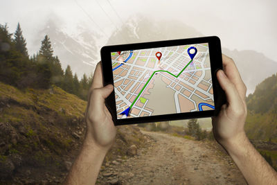 Midsection of person using mobile phone on mountain