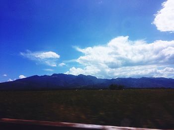 Scenic view of landscape and mountains against blue sky