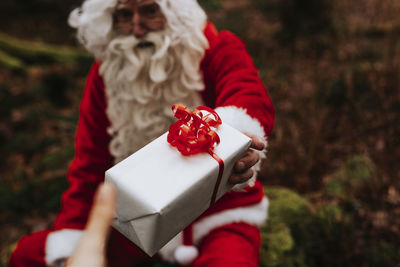 Man wearing santa costume holding present