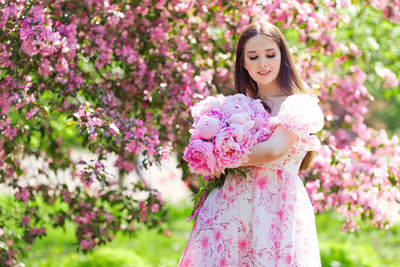 Low angle view of young woman holding flowers