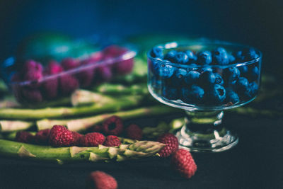 Close-up of berry fruits with asparagus on table