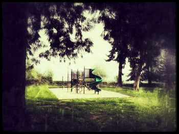 Empty park bench on field against sky