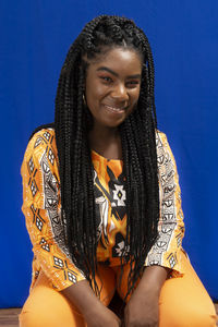 Young woman wearing colorful long clothes over blue background. natural expression.