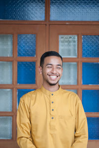 Smiling man standing against window