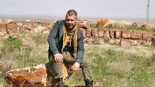 Young man standing on rock against wall