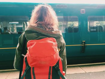 Rear view of backpack woman standing in front of train at station