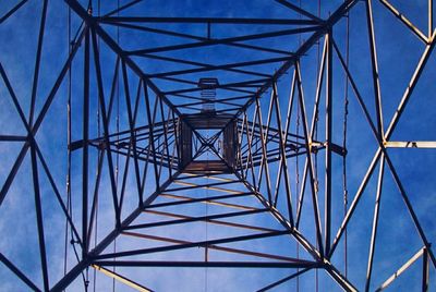 Low angle view of electricity pylon against blue sky