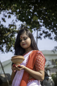 Young woman looking away while holding ice cream cone outdoors