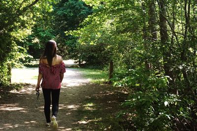 Rear view of young woman standing against trees