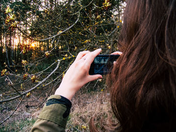 Close-up of hand holding mobile phone in forest