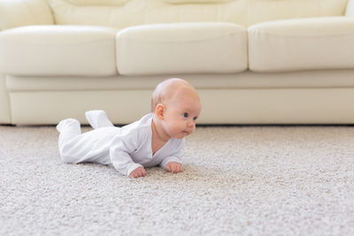 Full length of boy sitting on sofa at home