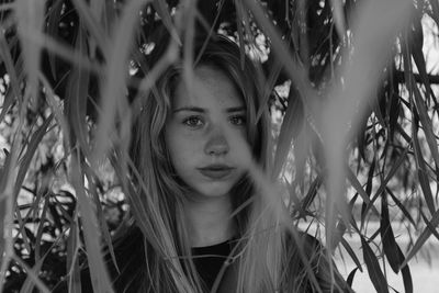 Portrait of young woman standing by plants