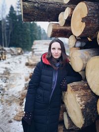 Portrait of young woman standing by log