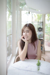 Portrait of smiling young woman sitting at table in cafe