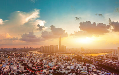 Aerial view of city against cloudy sky during sunset