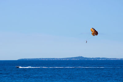 Person parasailing over sea against sky