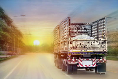 Vehicles on road against sky during sunset