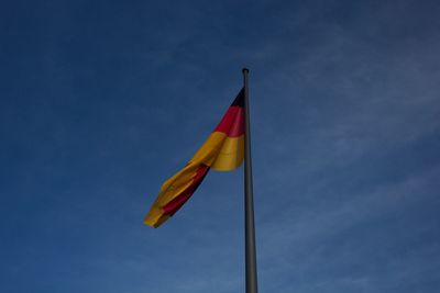 Low angle view of german flag against blue sky