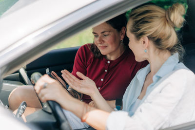 Portrait of female friends using mobile phone while sitting in car