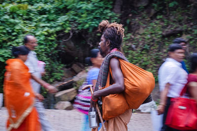 Side view of sadhu with bag walking by people on street