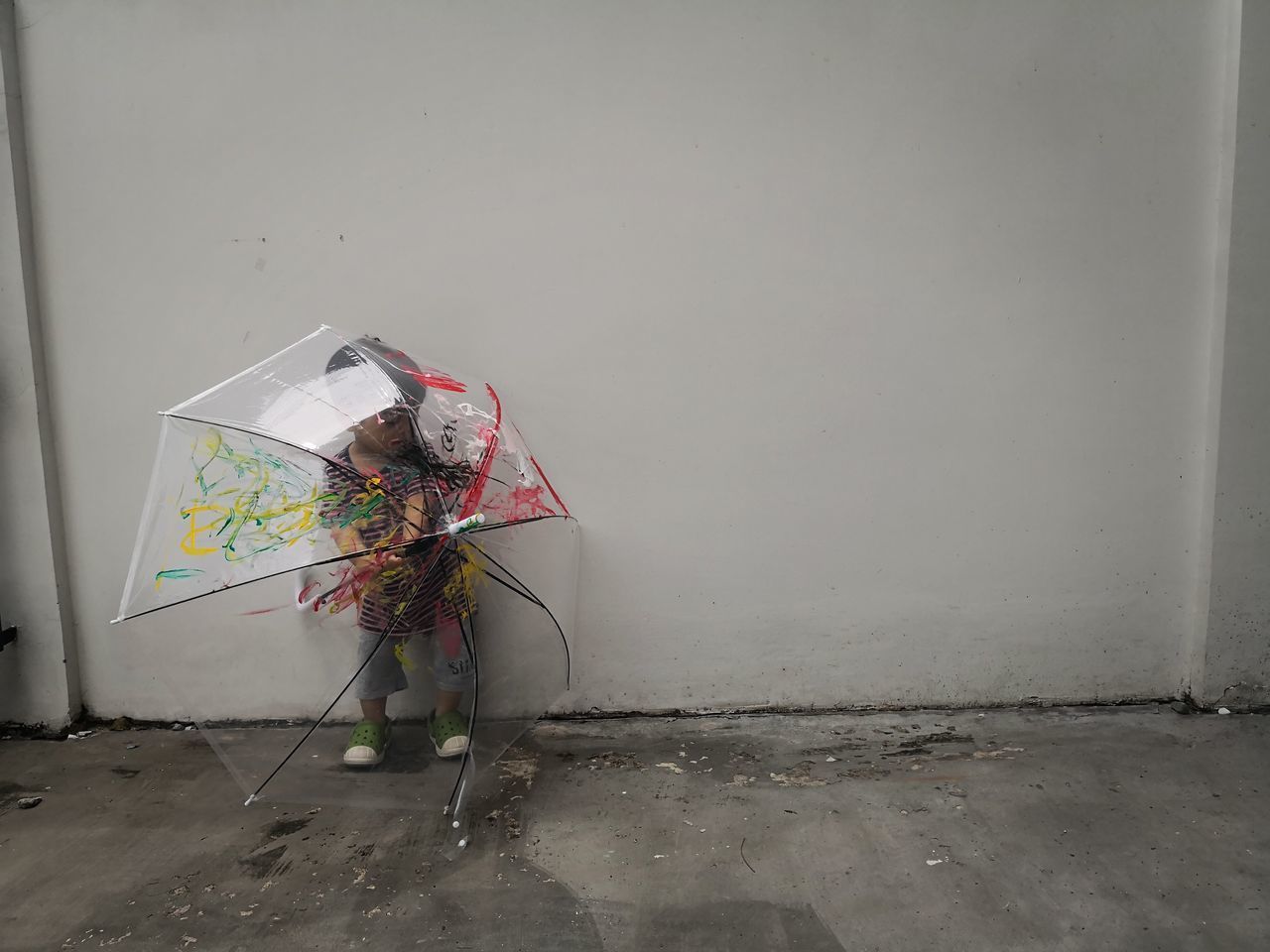 PERSON HOLDING UMBRELLA AGAINST WALL