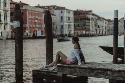 Boy sitting on pier against sky