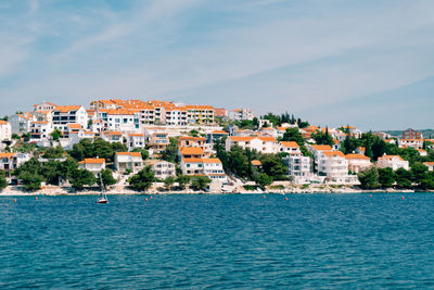 Buildings by sea against blue sky