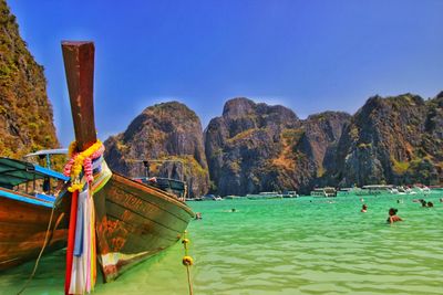 Longtail boats moored on sea against mountains at koh phi phi