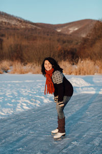 Smiling woman ice-skating on frozen lake
