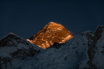 Tilt image of snowcapped mountain against clear sky at night during winter