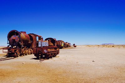 Abandoned train on desert against clear sky