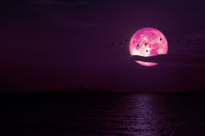 Full snow pink moon on night sky back cloud over dark sea, elements of this image furnished by nasa