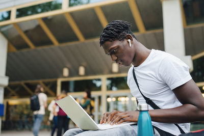 Male college student studying online on laptop in university campus