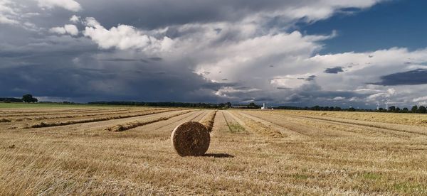 Hay bales on field against sky