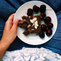 Personal perspective view of young woman enjoying slice of cake and cherries