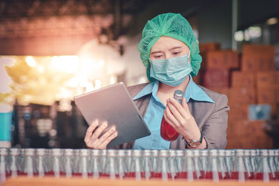 Woman using digital tablet while inspecting drinks in factory