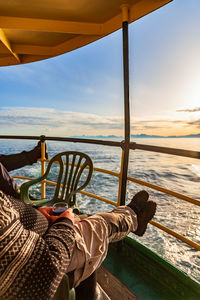 Low section of woman relaxing on boat in sea against sky
