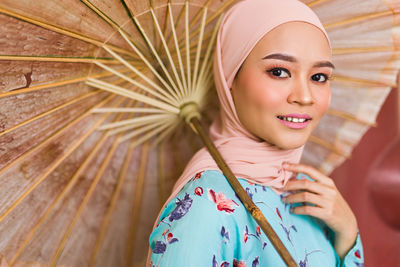 Portrait of a beautiful asian malay model in hijab posing for the camera holding an old umbrella.
