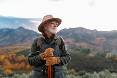 Man wearing hat standing against mountains