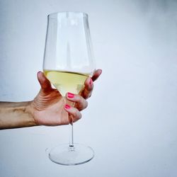 Close-up of hand holding glass over white background