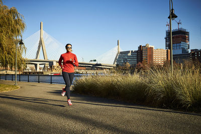 A woman running in front of the zakim bridge in boston.