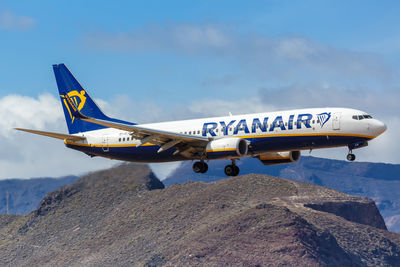 View of airplane flying over mountain against blue sky